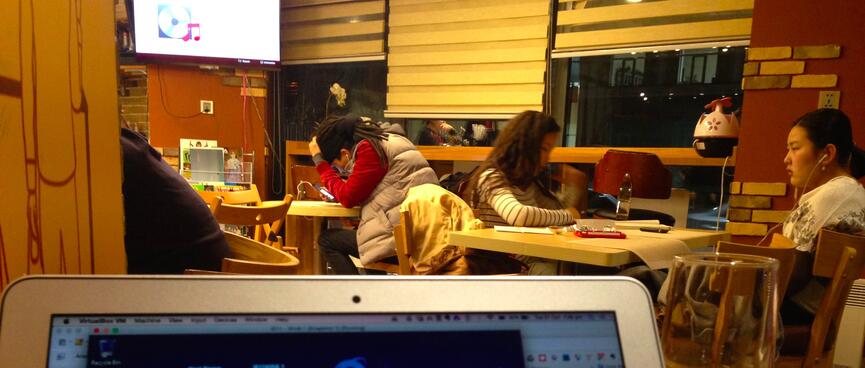 Students study with their earphones in, while music plays through a television.