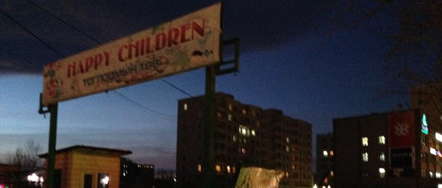 A sign above a car park entrance reads 'Happy Children'.
