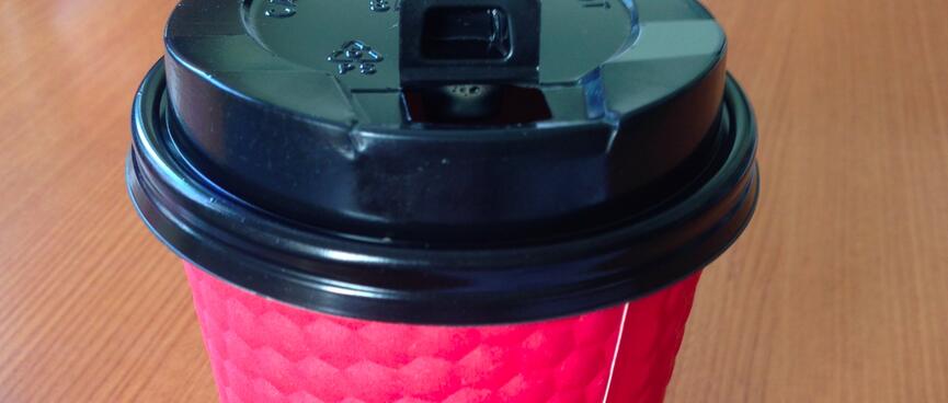 A red paper cup with a black plastic lid.