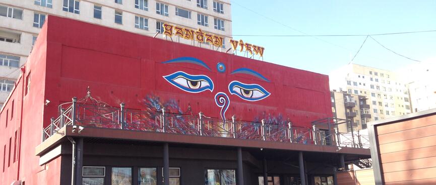 A pair of sleepy eyes is painted on the side of a red building.