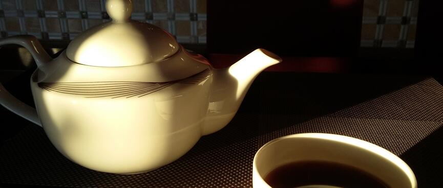 A white teapot and cup with matching pattern.