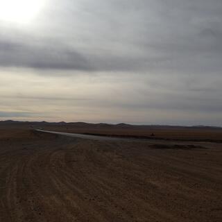 Barren brown steppes extending to low hills at the horizon.