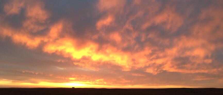 Sunset illuminates the underside of a mottled cloudscape.