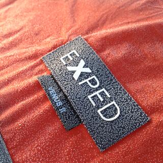 The black label and orange fabric of my EXPED VENUS II tent are covered by frozen droplets.