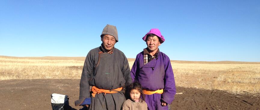 Two men and a young girl wearing shin length cloaks, fabric belts, knee high boots and brimless hats.
