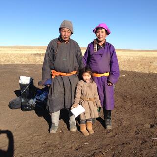 Two men and a young girl wearing shin length cloaks, fabric belts, knee high boots and brimless hats.