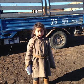 A little girl poses in front of a flatdeck truck.