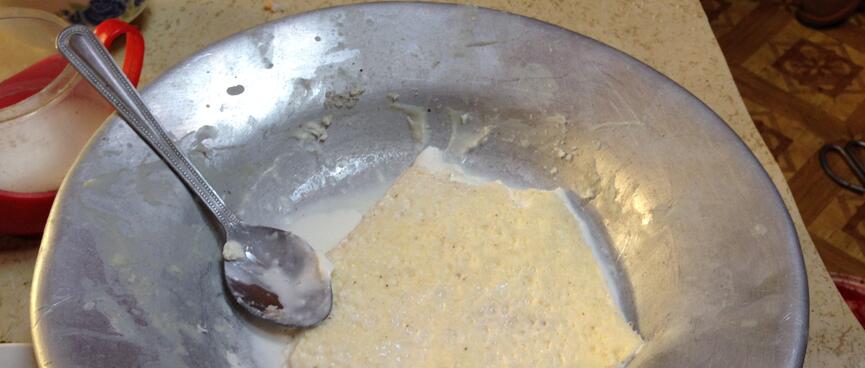 A shallow pancake in a puddle of milk, on a metal dinner plate.