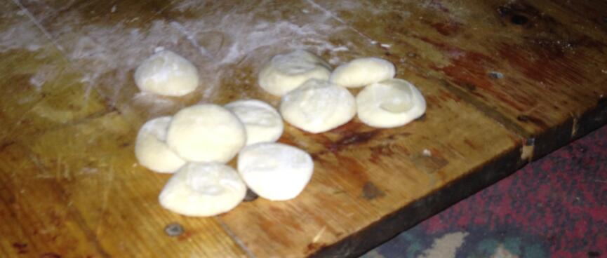 Ten flat buns sitting on a floury table.