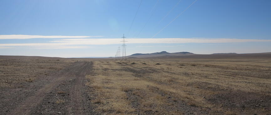 A gravel road through the flat grassy steppe.