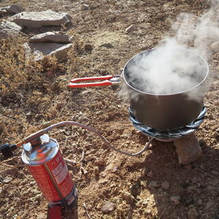 A steaming pot on top of a metal gas cooking stove.