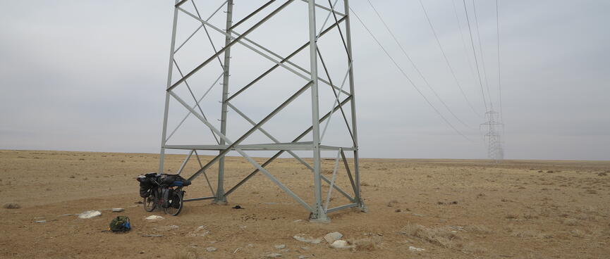An infinitely long line of power pylons in an otherwise barren landscape.