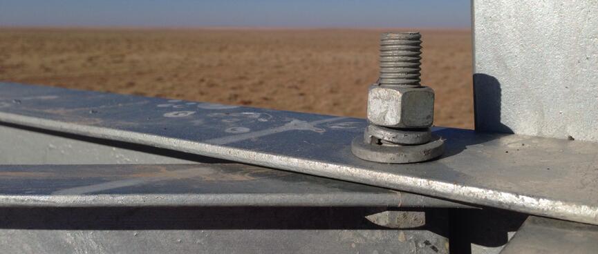Close-up of a nut and bolt on the metal frame of a power pylon.