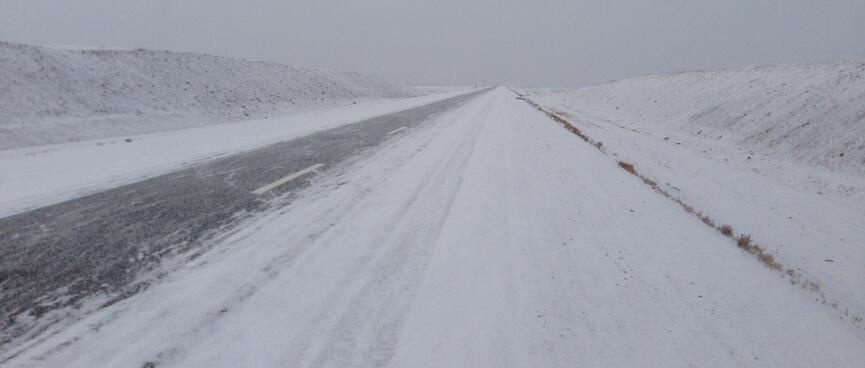 A thin sliver of the clear asphalt in an otherwise snow covered highway.