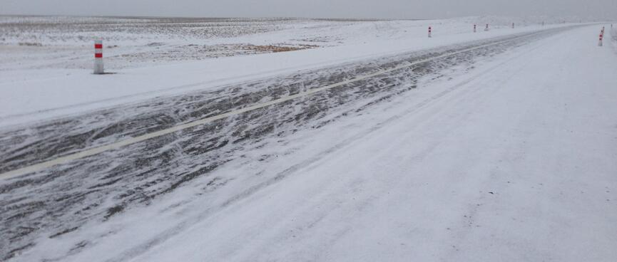 Snow is smeared in all directions on the asphalt highway.