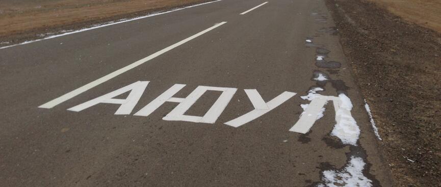 A foreign sign on the asphalt appears to read AHOY.