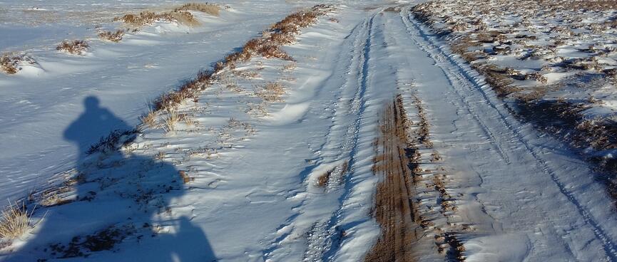 Deep snow lies in the gullies of a four wheel drive track. Fresh tyre tracks on the tops reveal the sand below.