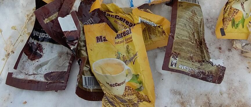 Brown and yellow sachets of breakfast drinks next to a steaming pot.