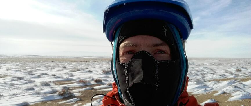 Dressed balaclava, hoodie and helmet, I pose in front of a scene of snowdrifts.