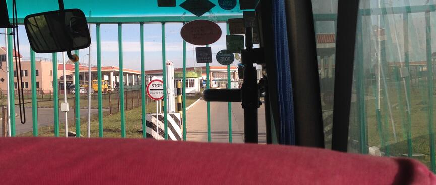 A green gate and a bilingual Stop sign stop us from covering the last short stretch of road into Russia.