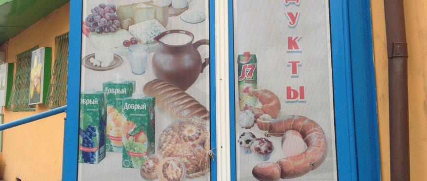 A poster advertises bread, cheese, sausage, milk and fruit juice, in Chita.