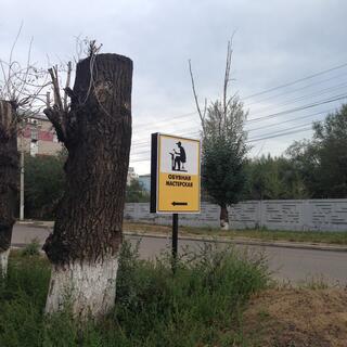 A roadside sign depicts a man hammering a new sole onto an upturned boot, in Chita.