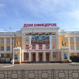 Bronze statues of soldiers stand guard outside a solid yellow building, in Chita.