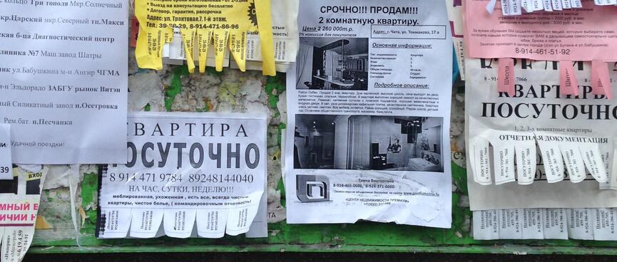 Real estate, printed and handwritten advertisements on a noticeboard, in Chita.