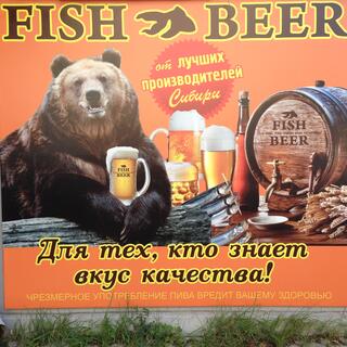 A large brown bear holds a large glass of beer between his paws.