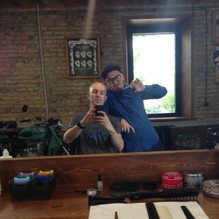 Germin leans on my chair while I take a photo of us in the mirror, at Bros hair salon in Chita.