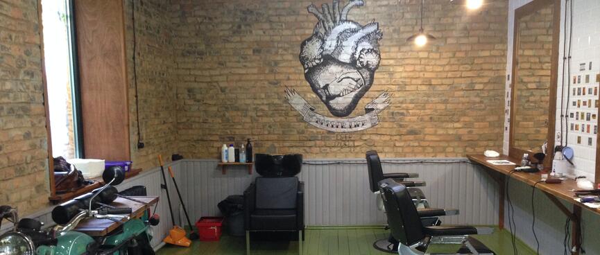 A row of barber chairs, an old motorcycle, and a illustration of a heart and two hands shaking.