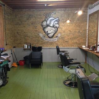 A row of barber chairs, an old motorcycle, and a illustration of a heart and two hands shaking.