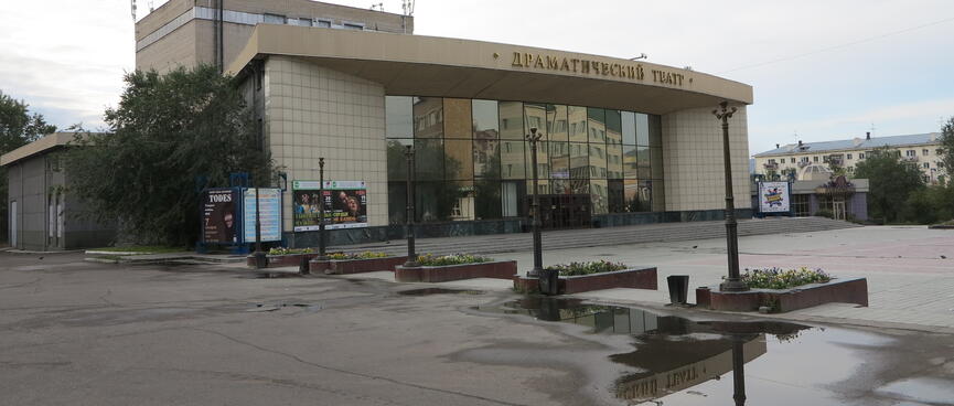 A squat building with a curved frontage, reflective windows and tiled walls, displays a few stage play posters, in Chita.