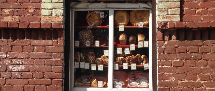 An arched window cut out in a brick wall hosts an elaborate display of baked goods, in Chita.