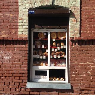An arched window cut out in a brick wall hosts an elaborate display of baked goods, in Chita.