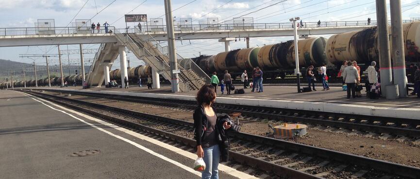 Wanna stands on an empty platform while a long line of tanker wagons roll by, in Chita.