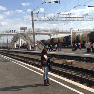 Wanna stands on an empty platform while a long line of tanker wagons roll by, in Chita.