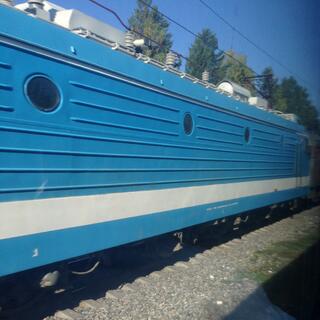 A mid blue locomotive with small portholes and horizontal metal ribbing.