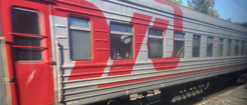 A large red Russian Railways logo brightens up a grey passenger carriage.