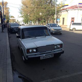 A shiny white Lada is parked on a side street.