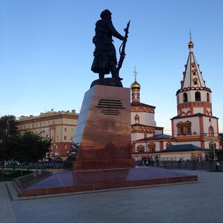 A statue of a Cossack soldier holding a rifle, and some ornate buildings.