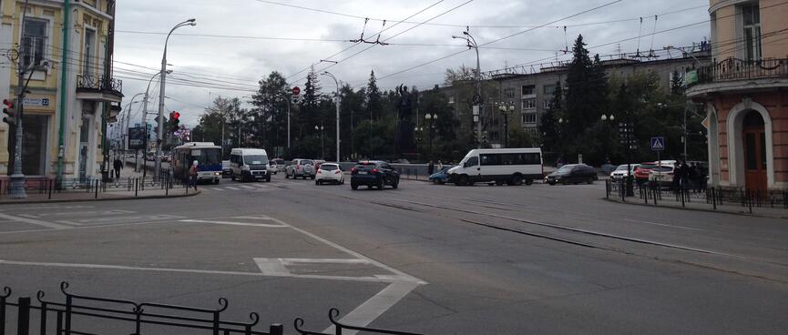 A large intersection is crossed by buses, vans, cars, tram lines and trolley bus wires.
