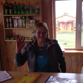 A Russian woman waves from behind the counter of her shop in Maloye Goloustnoye.