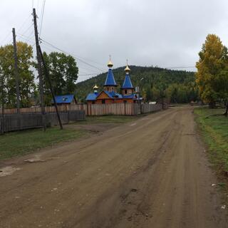 A wooden church in Maloye Goloustnoye has blue towers and golden domes.