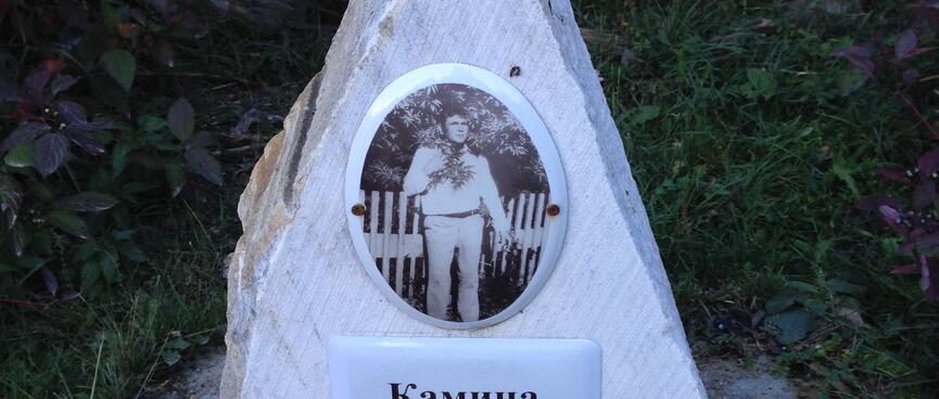 A wedge of white stone bears a plaque and a photograph of a man.