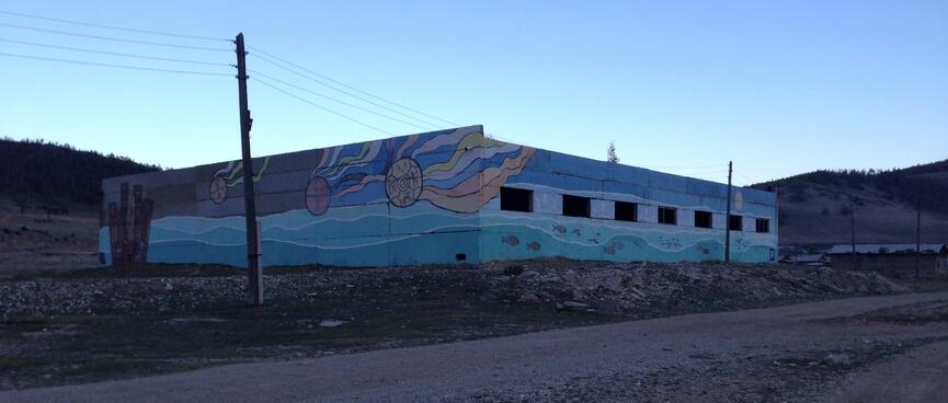 A shallow building with slit windows is painted in a mural.