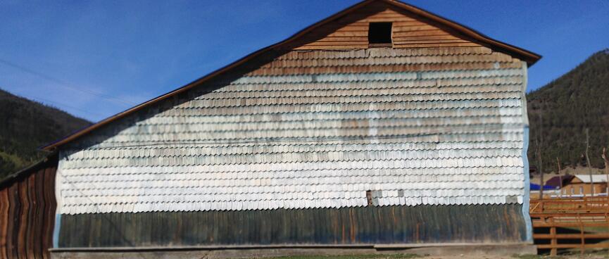 A large wooden barn is covered in wooden tiles.