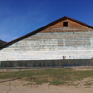 A large wooden barn is covered in wooden tiles.