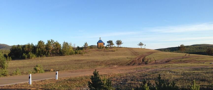 A small wooden church sits on top of a low hill.