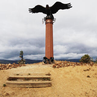 A statue of an eagle sits atop a barren hilltop.